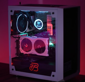A gaming computer with visible internal components such as cooling fans and LED lights in a transparent case. The lighting emits a colorful glow with shades of purple, blue, and red.